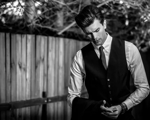 Elegant handsome man in classical suit poses near wooden fence — Stock Photo, Image