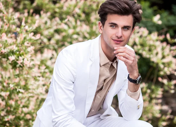 Elegante knappe man in een wit kostuum buiten — Stockfoto