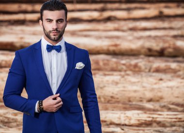 Genç güzel şık adam ağaç gövdeleri karşı olarak arka plan açık portresi