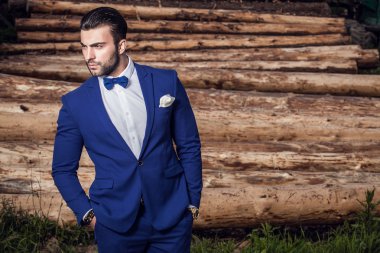 Genç güzel şık adam ağaç gövdeleri karşı olarak arka plan açık portresi