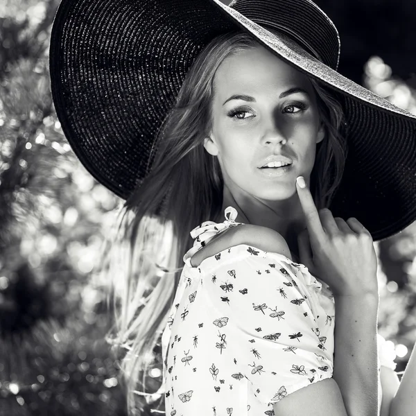 Outdoors portrait of beautiful young blonde woman in black classic hat — Stock Photo, Image