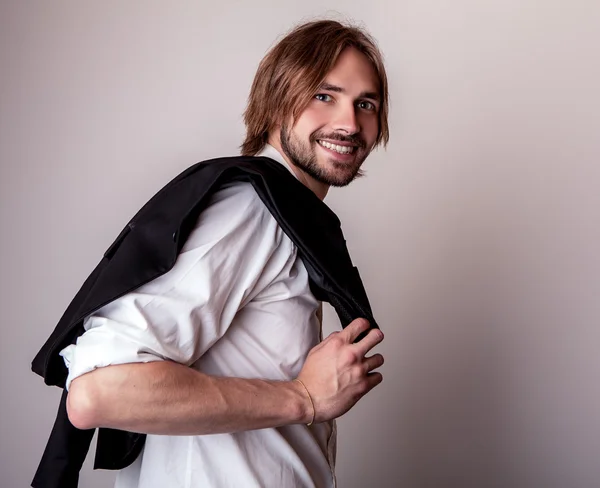 Elégant jeune homme aux cheveux longs pose en studio — Photo