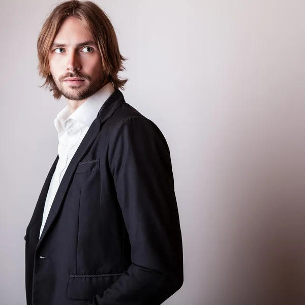 Elégant jeune homme aux cheveux longs pose en studio — Photo