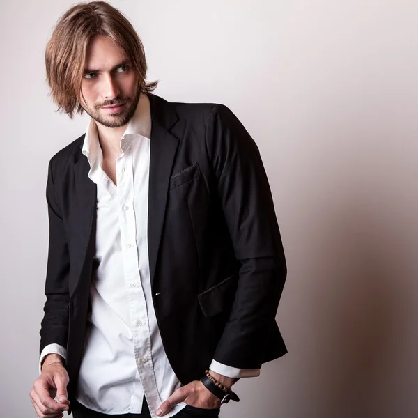 Elegante jovem longo cabelo bonito homem pose no estúdio — Fotografia de Stock