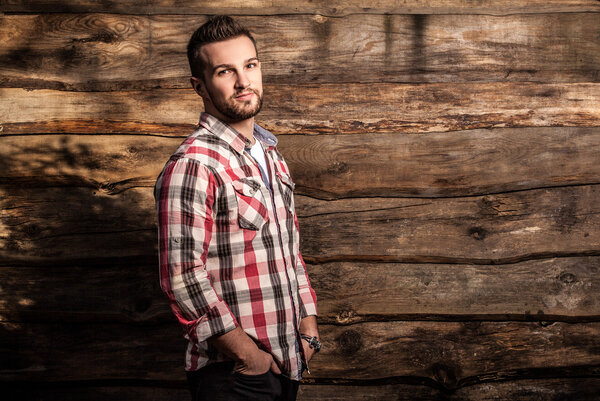 Portrait of young beautiful fashionable man against wooden wall