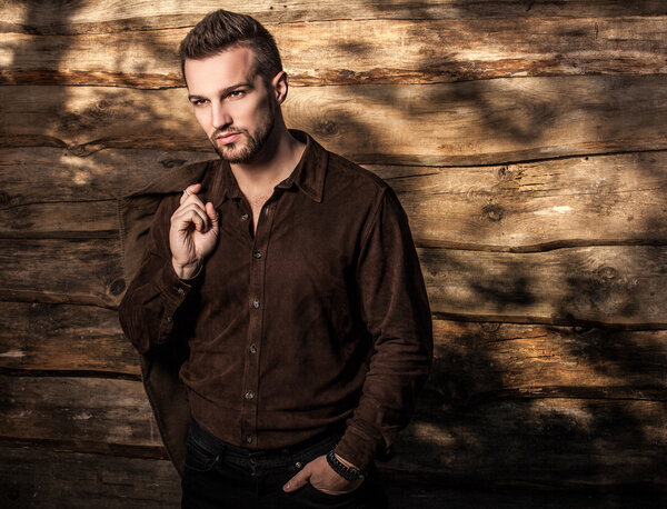 Portrait of young beautiful fashionable man against wooden wall