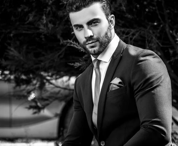 Elegante hombre guapo en traje clásico pose al aire libre. Foto en blanco y negro — Foto de Stock