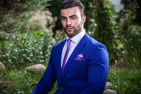 Elegante hombre guapo en traje azul clásico pose al aire libre —  Fotos de Stock