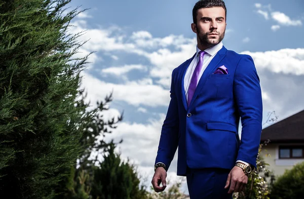 Elegante bell'uomo in costume classico blu posa all'aperto — Foto Stock