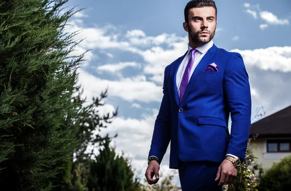 Elegante hombre guapo en traje azul clásico pose al aire libre — Foto de Stock