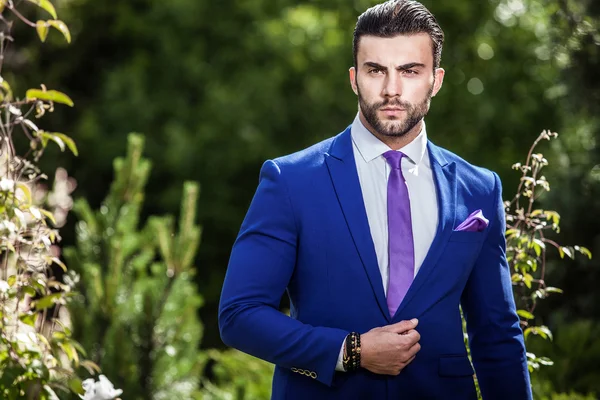 Elegante knappe man in klassieke blauw kostuum vormen buiten — Stockfoto