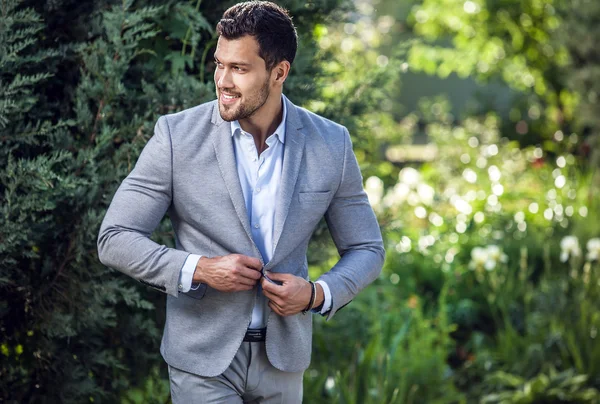 Elegante homem bonito em jaqueta clássica posa ao ar livre — Fotografia de Stock