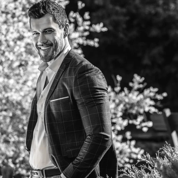 Elegante hombre guapo en chaqueta clásica posa al aire libre —  Fotos de Stock