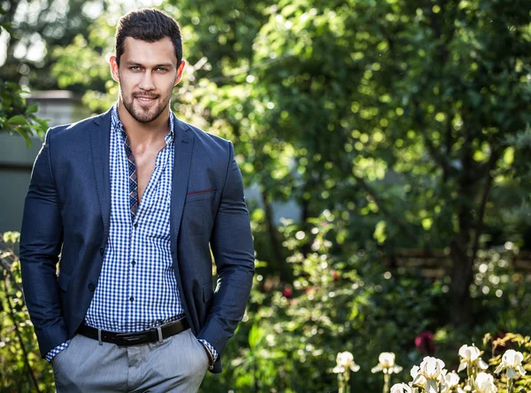 Elegante hombre guapo en chaqueta clásica posa al aire libre — Foto de Stock