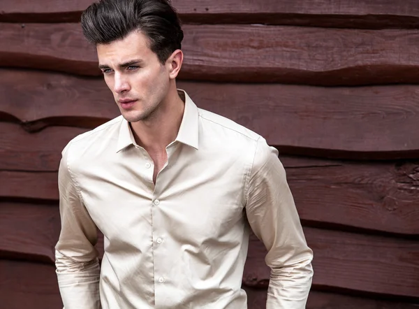 Retrato de joven hermoso hombre de moda en contra de la pared de madera — Foto de Stock