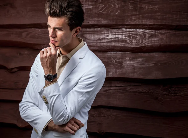 Portrait of young beautiful fashionable man in white costum against wood wall — Stok Foto