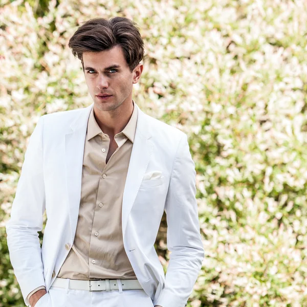 Elegantní pohledný muž v bílém kostýmu představovat venkovní — Stock fotografie