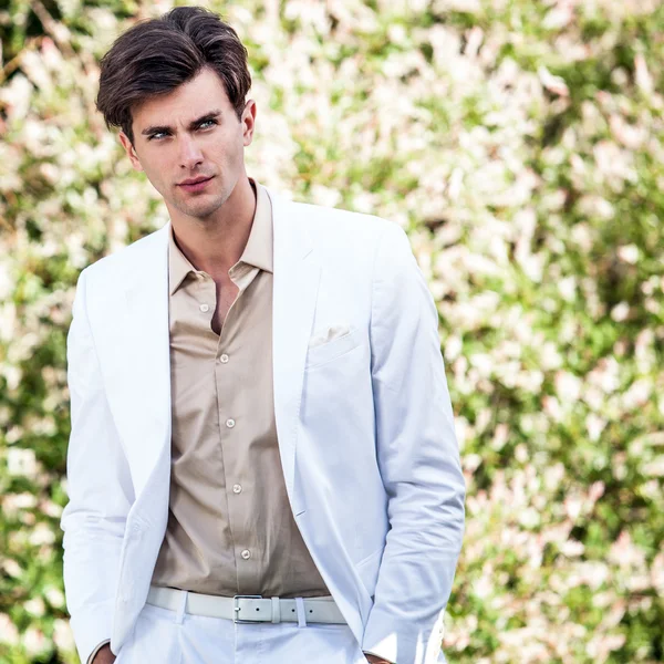 Elegante hombre guapo en traje blanco pose al aire libre — Foto de Stock