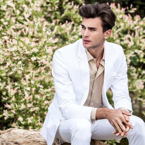 Eleganter schöner Mann im weißen Kostüm posiert im Freien — Stockfoto