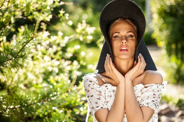Outdoors portrait of beautiful young blonde woman in black classic hat — Stock Photo, Image