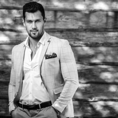 Ahşap duvara yaslanmış genç ve şık bir adamın portresi.