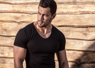 Genç güzel sportif adam t-shirt ahşap duvar karşı portresi