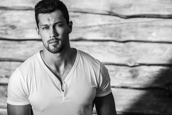 Retrato de joven hermoso hombre deportivo en camiseta contra pared de madera —  Fotos de Stock