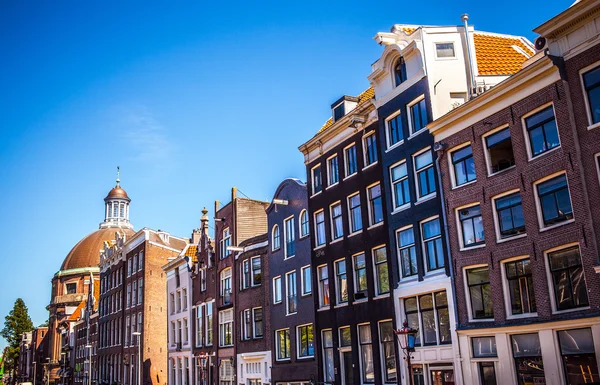 AMSTERDAM, NETHERLANDS - AUGUST 15, 2016: Famous buildings of Amsterdam city centre close-up. General landscape view of city streets and traditional Dutch architecture. Amsterdam - Netherlands. — Stock Photo, Image