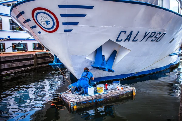 Amsterdam, Hollanda - 15 Ağustos 2016: Adam çalışan bir Sal üzerinde yolcu tekne boyar. Amsterdam - Hollanda. — Stok fotoğraf