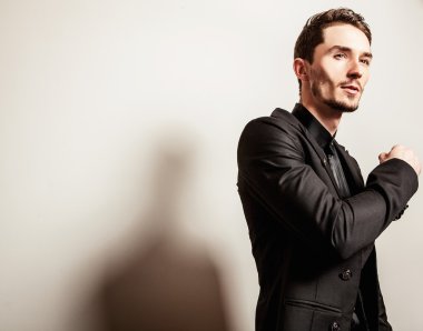 Siyah kostümlü zarif genç yakışıklı adam. Studio moda portre.