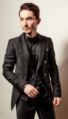 Siyah kostümlü zarif genç yakışıklı adam. Studio moda portre.