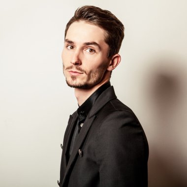 Siyah kostümlü zarif genç yakışıklı adam. Studio moda portre.