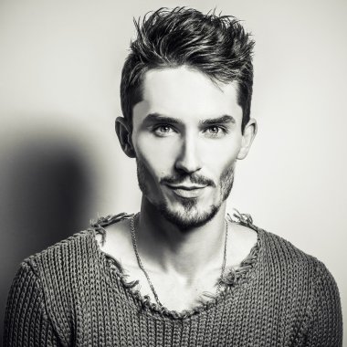 Siyah-beyaz stüdyo örme kazak genç yakışıklı adam portresi. Yakın çekim fotoğraf.