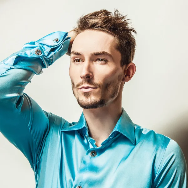 Elegante jonge knappe man in blauwe zijde shirt. Studio mode portret. — Stockfoto