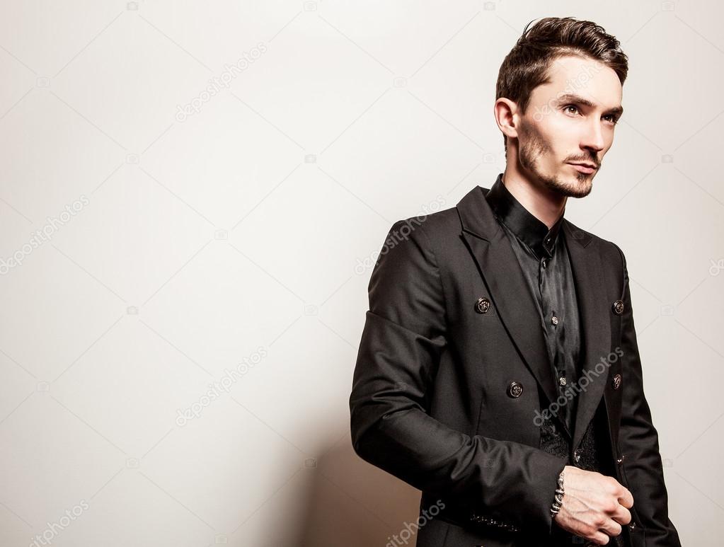 Elegant young handsome man in black costume. Studio fashion portrait.