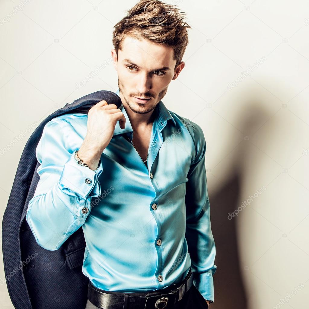 Elegant young handsome man in blue silk shirt. Studio fashion portrait.