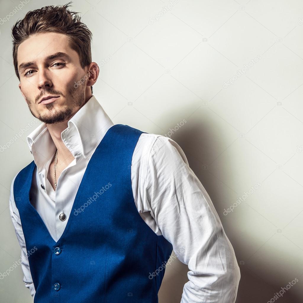 Elegant young handsome man in white shirt & vest. Studio fashion portrait.