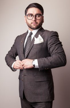 Gri kostümlü zarif genç yakışıklı adam. Studio moda portre.
