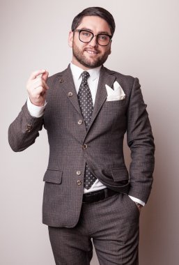 Gri kostümlü zarif genç yakışıklı adam. Studio moda portre.