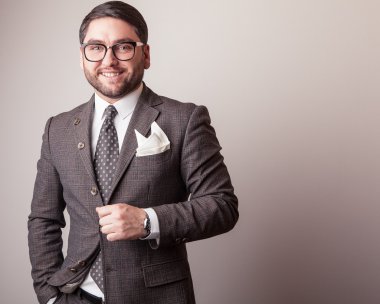 Gri kostümlü zarif genç yakışıklı adam. Studio moda portre.