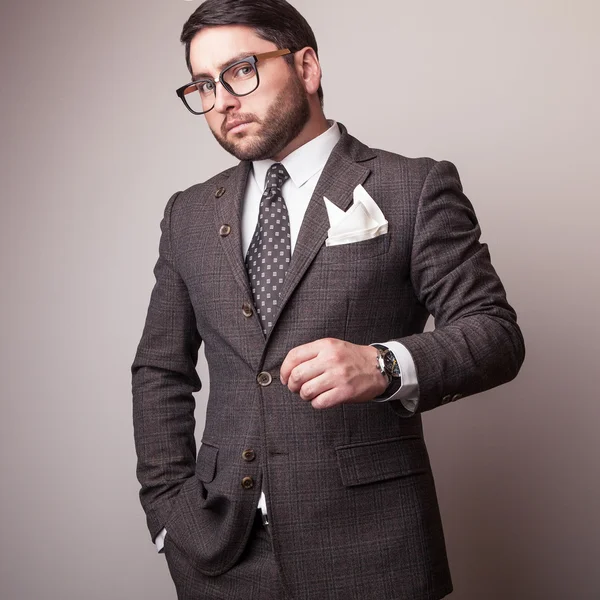 Elegantní mladý pohledný muž v šedém kostýmu. Portrét módní Studio. — Stock fotografie