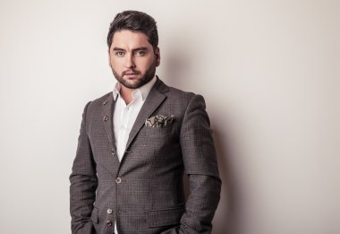Gri kostümlü zarif genç yakışıklı adam. Studio moda portre.