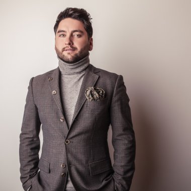 Gri kostümlü zarif genç yakışıklı adam. Studio moda portre.