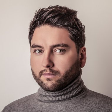 Gri süveterli zarif genç yakışıklı adam. Studio moda portre.