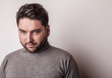Gri süveterli zarif genç yakışıklı adam. Studio moda portre.
