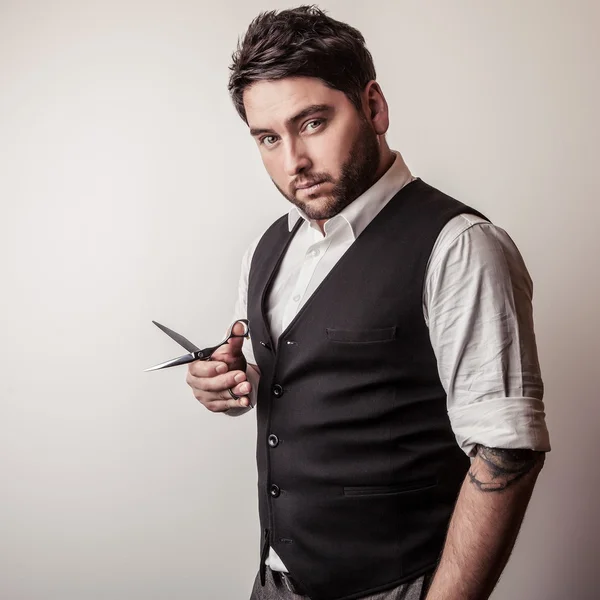 Elegant young handsome hairdresser with scissors in hand. Studio fashion portrait. — Stock Photo, Image