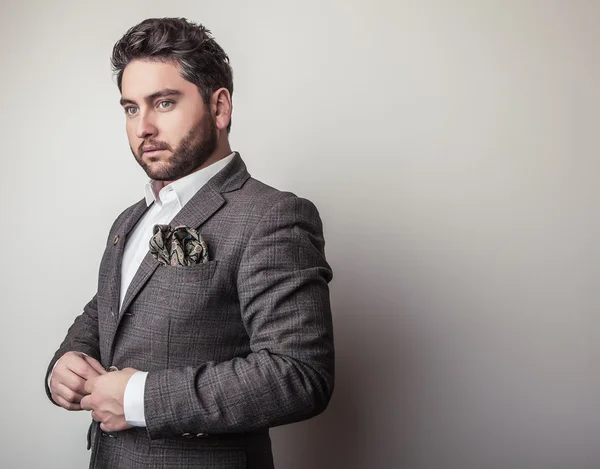 Eleganter junger gutaussehender Mann im grauen Kostüm. Modeporträt im Studio. — Stockfoto