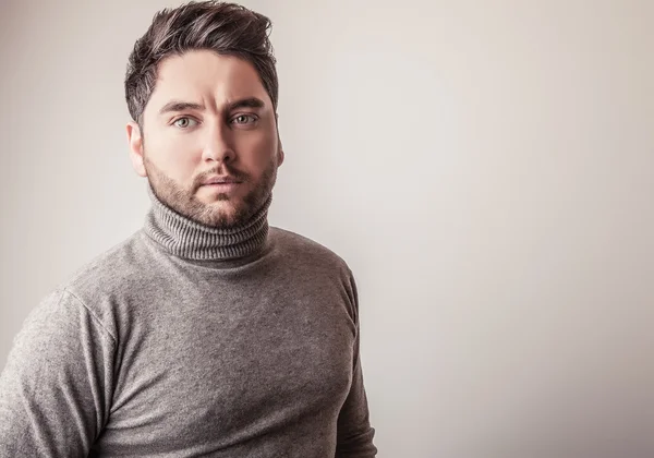 Elégant jeune homme beau en pull gris. Studio portrait de mode . — Photo