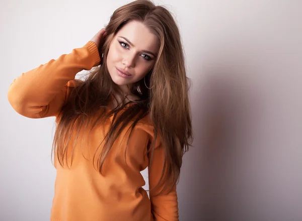 Junges sinnliches Model in lässigem orangefarbenem Pullover posiert im Studio. — Stockfoto