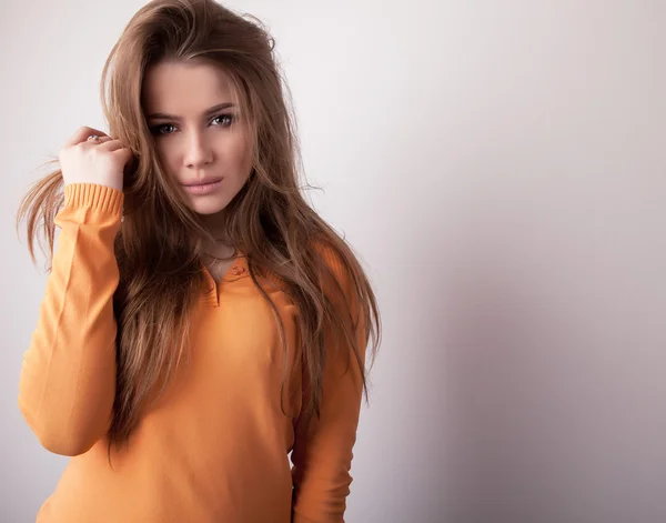 Young sensuell & skönhet modell flicka iin casual orange tröja posera i studio. — Stockfoto